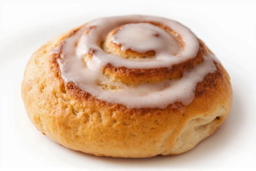 Close-up of a sliced cinnamon roll showing perfect spiral layers with melted icing dripping between the layers