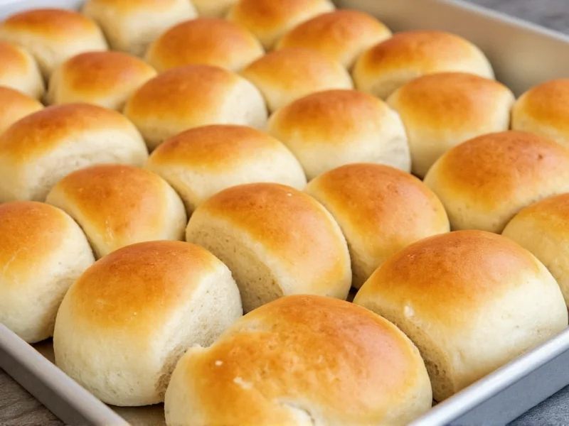 Golden homemade dinner rolls on baking sheet