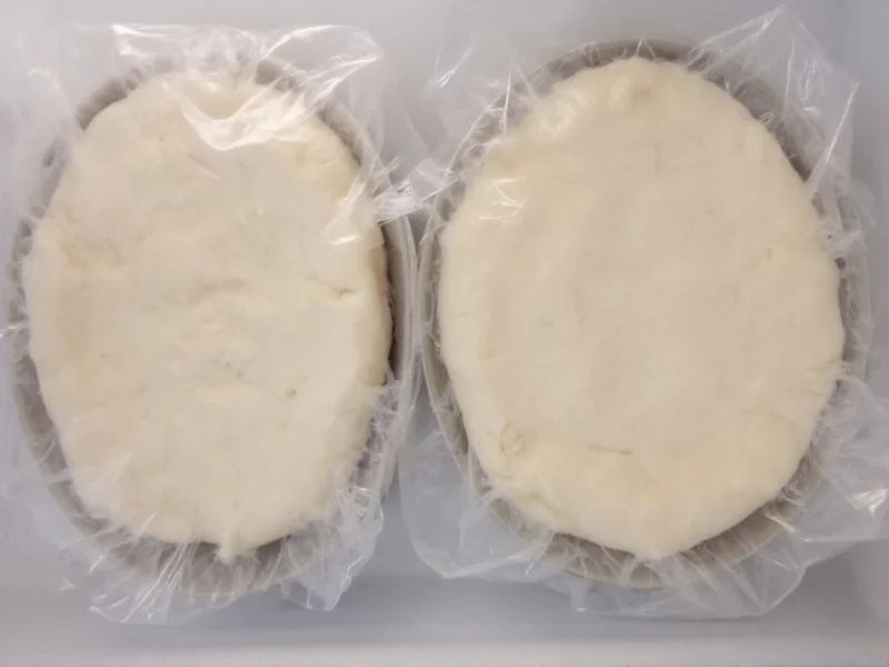 Two wrapped pie dough disks chilling in refrigerator
