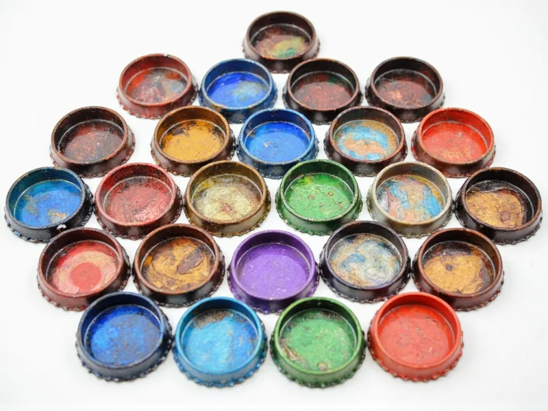 19 plastic bottle caps arranged in hexagonal pattern with paint and glue