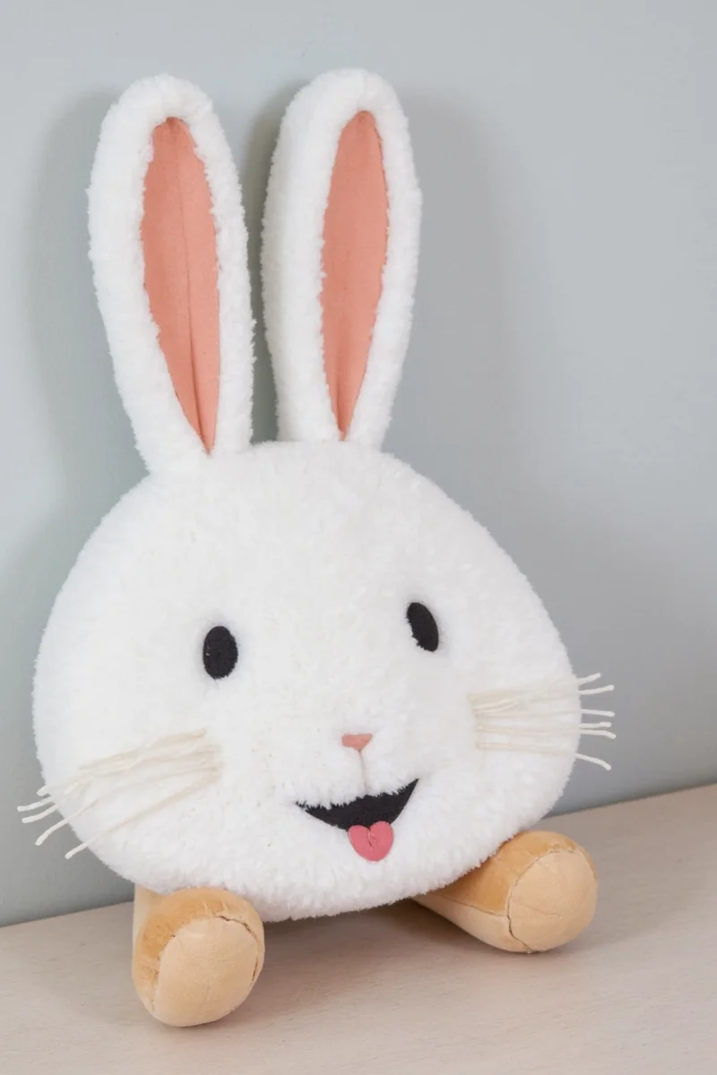 A modern living room with a custom-designed rabbit playpen made from natural wood and soft cushions