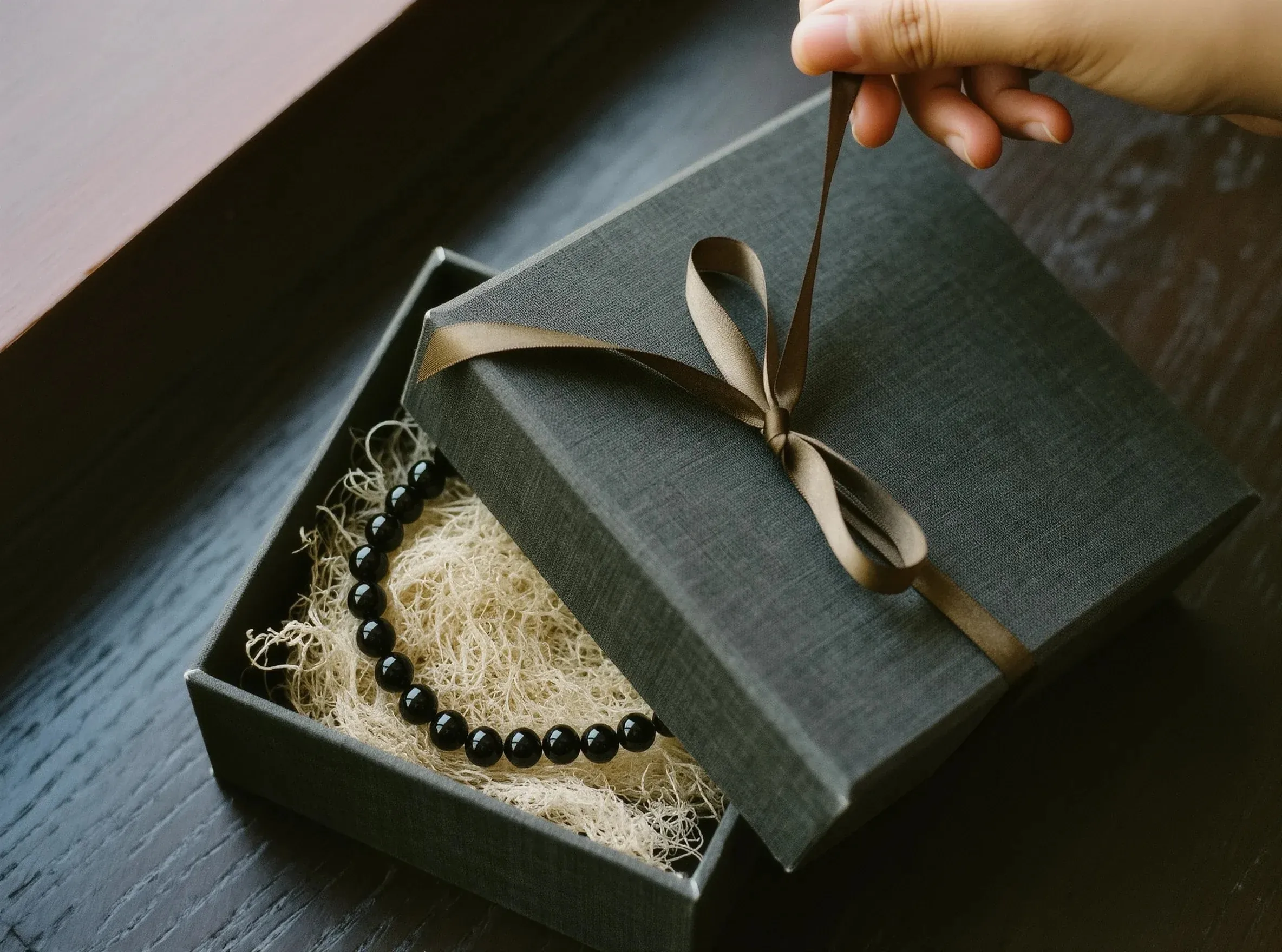 Sovereign Stillness Jewelry Privacy: An artisan hand opening a silk ribbon on a premium gift box, symbolizing the safe custody of your data.