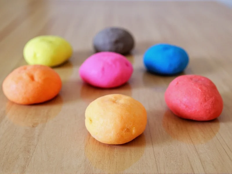 Colorful no-cook playdough balls on wooden table