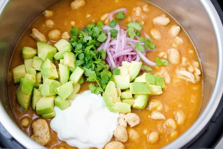 Finished bowl of instant pot white chicken chili with various topping options including avocado, sour cream, and cilantro