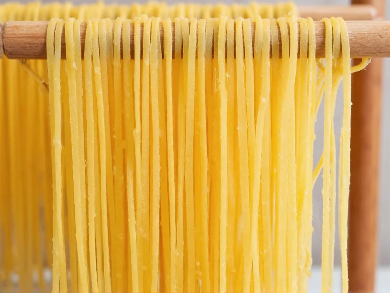 Freshly cut spaghetti strands on wooden drying rack