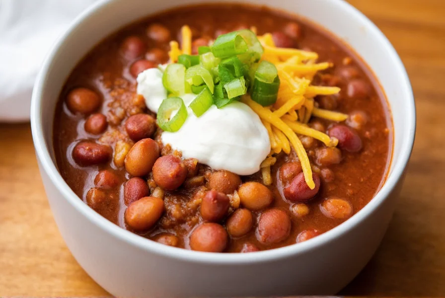 Finished bowl of pinto bean chili with toppings including sour cream, cheese, and green onions