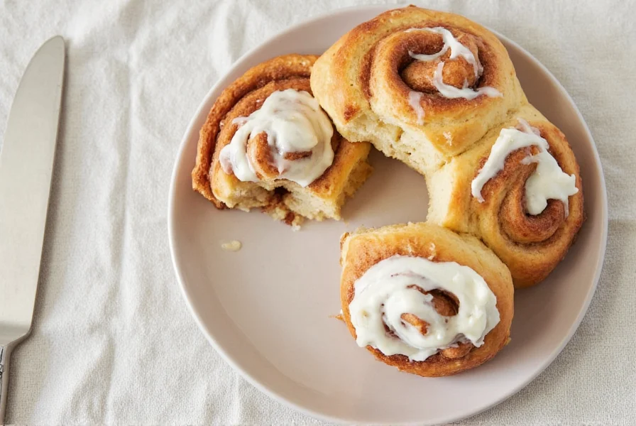 Close-up of Pillsbury cinnamon rolls with glossy heavy cream frosting drizzled over golden brown rolls on a white ceramic plate