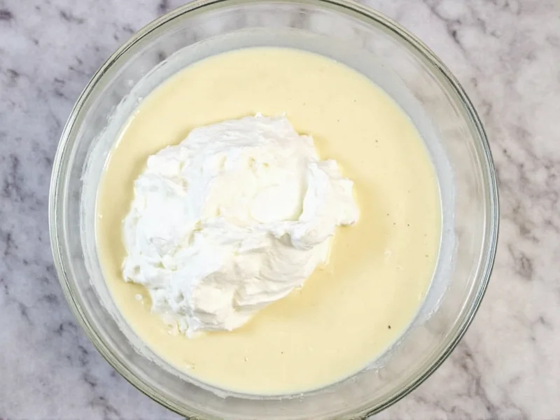 Whipped cream folded into condensed milk mixture in glass bowl