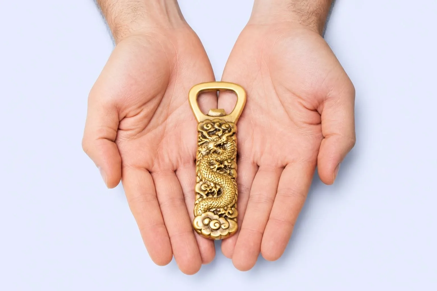 Brass dragon bottle opener in open hands