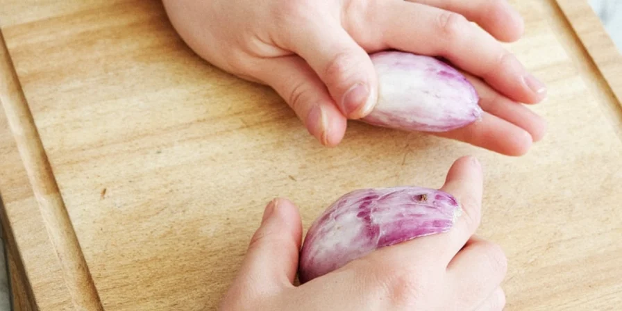 Flaked onions being sprinkled from a frozen jar into a pan