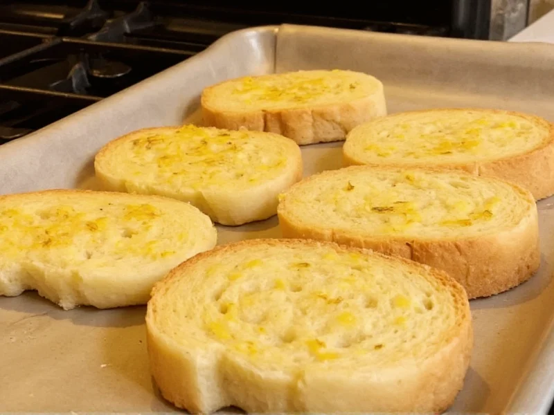 Golden garlic bread slices fresh from oven on baking sheet