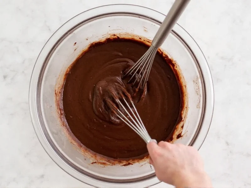Mixing brownie batter in bowl with melted chocolate