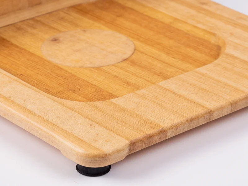 Close-up of wooden bread slicer base with non-slip feet and adjustable gauge