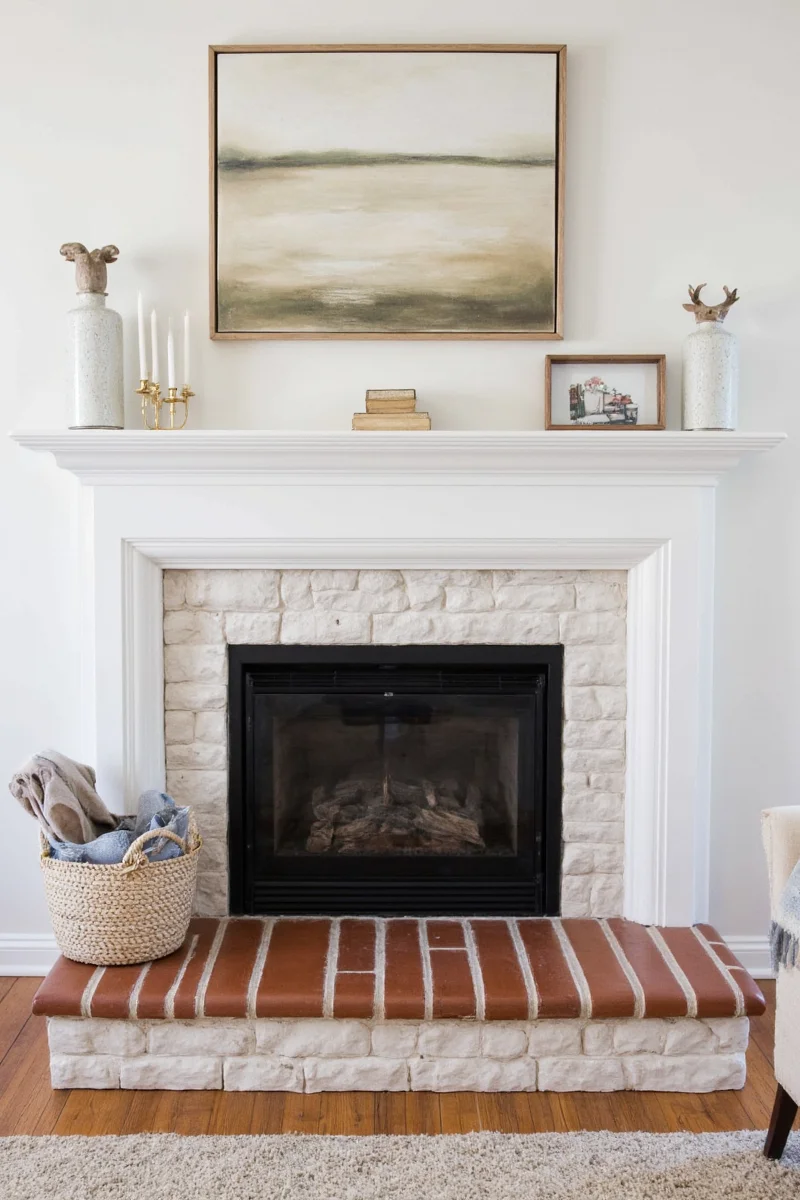 Floating shelves with children's art displayed above a white painted stone fireplace