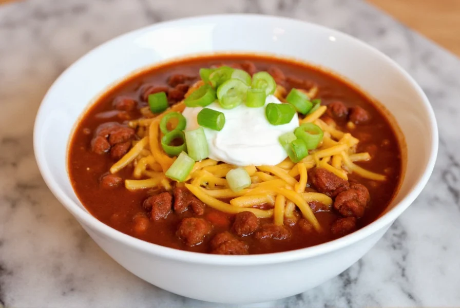 Finished bowl of homemade chili with melted cheese, sour cream, and green onions as toppings