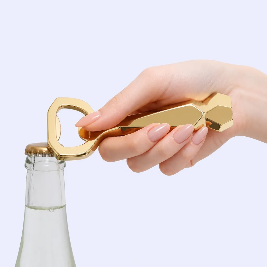 Hand gripping the faceted gold bottle opener against a bottle neck