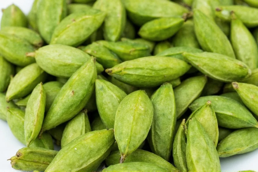 Close-up photograph of fresh green cardamom pods showing their triangular shape and vibrant color against a wooden cutting board