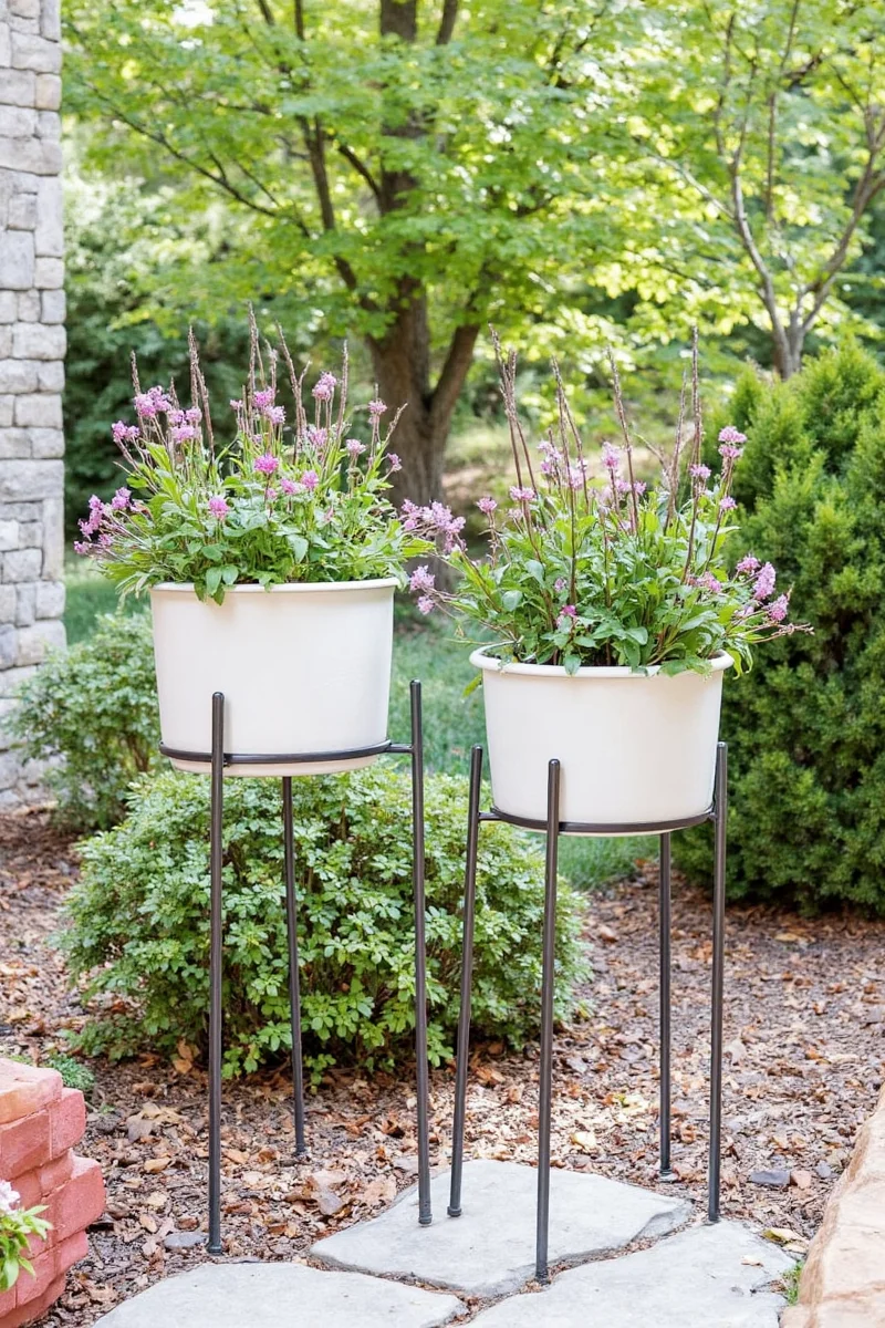 Modway Adjustable 4-Tier Metal Plant Stand placed on a balcony with hanging herbs and succulents above a cat lounging below