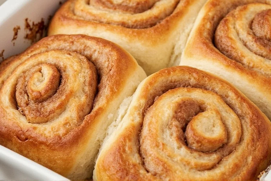 Finished cinnamon rolls with cream cheese frosting drizzled on top, showing perfect swirl pattern