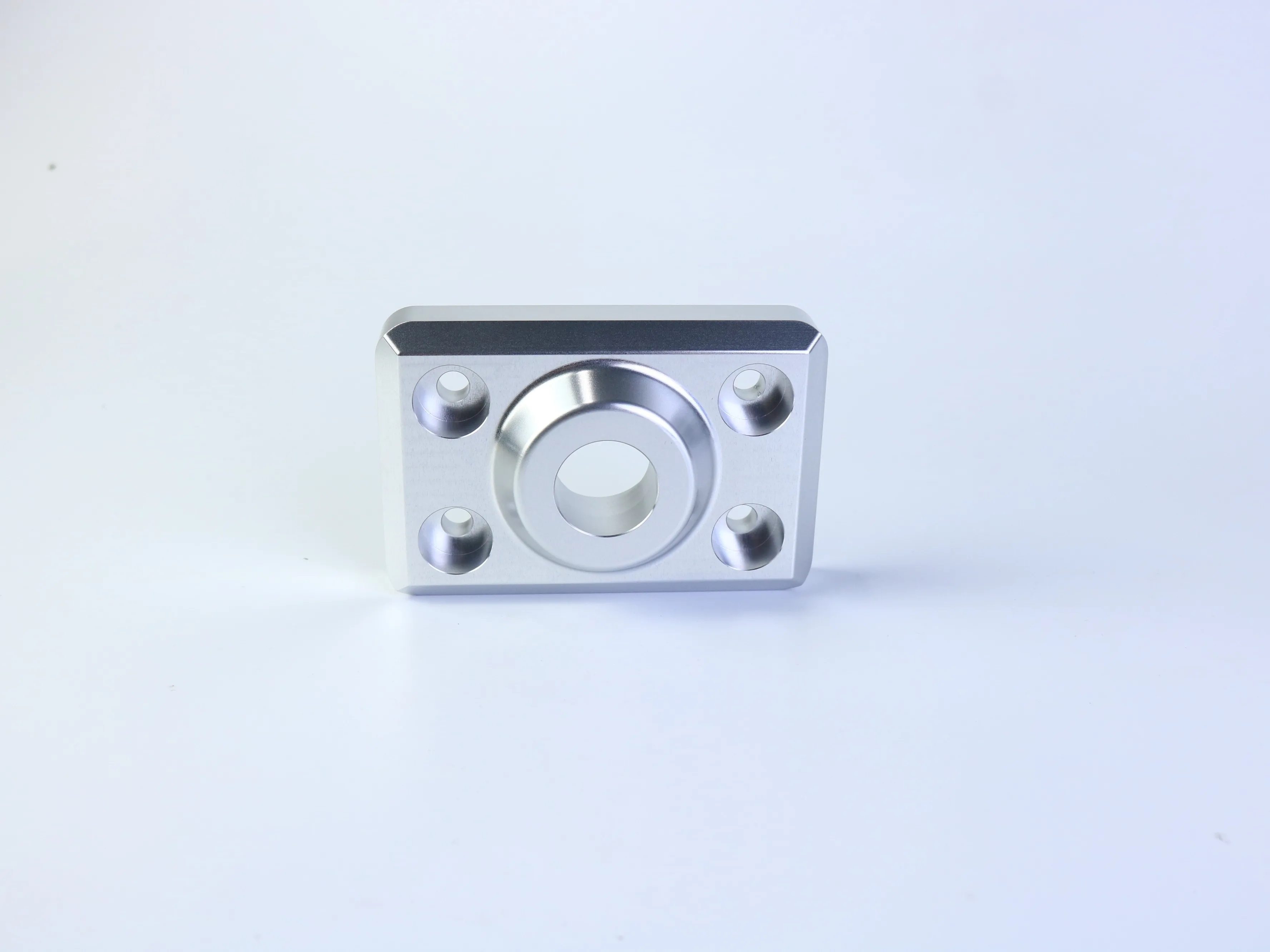 CNC machined rectangular mounting plate with a central circular boss and four mounting holes