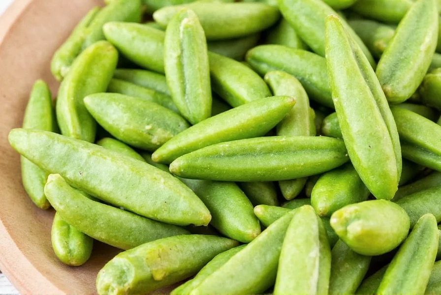 Close-up photograph of green cardamom pods showing triangular shape and pale green color against wooden cutting board